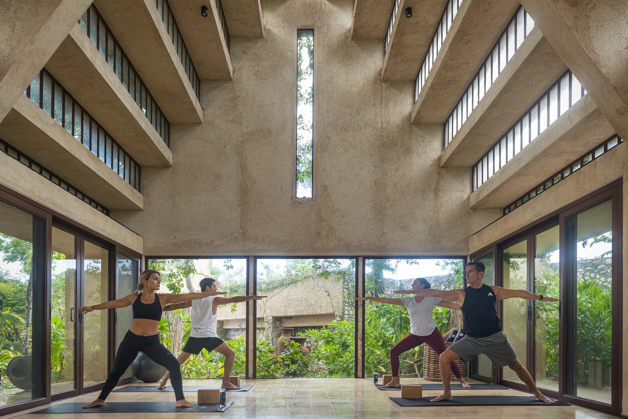 Salón de yoga de doble altura abierto a la vegetación